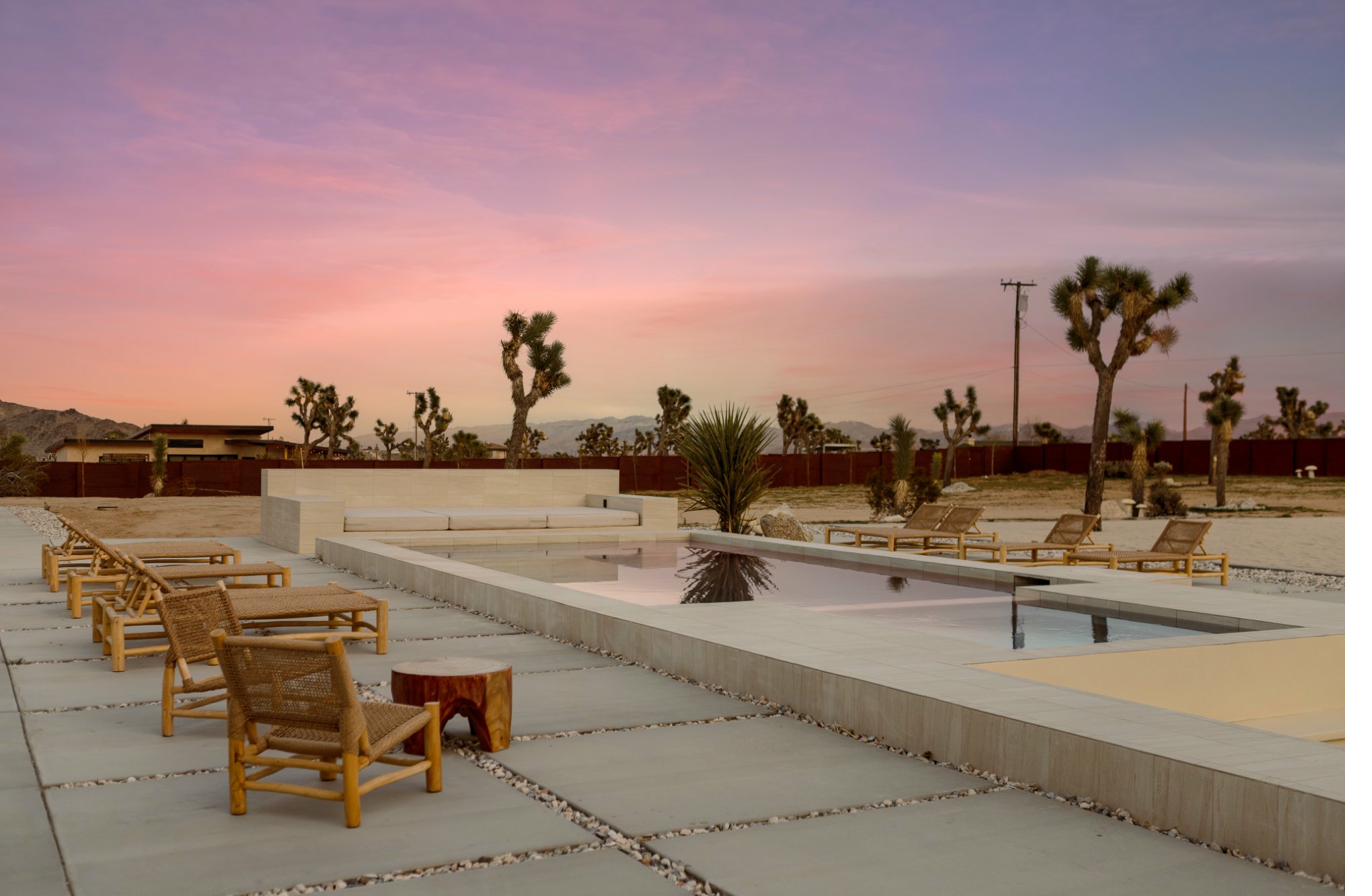 Pool lounge chairs at pink and purple sunset