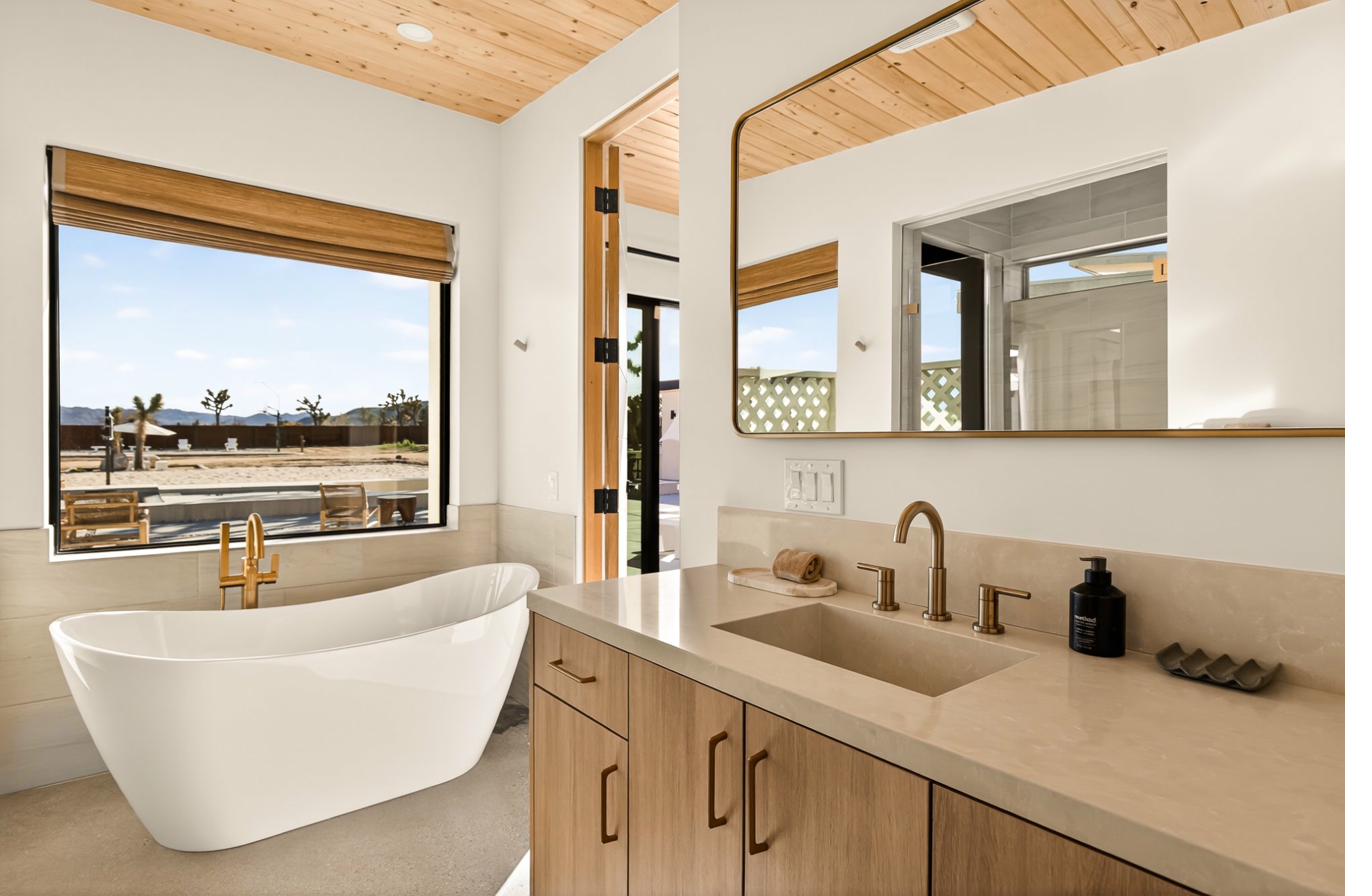 Freestanding soaking tub with desert-view window and gold fixtures